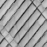 Close-up of a chain-link fence in black and white showcasing a textured pattern.